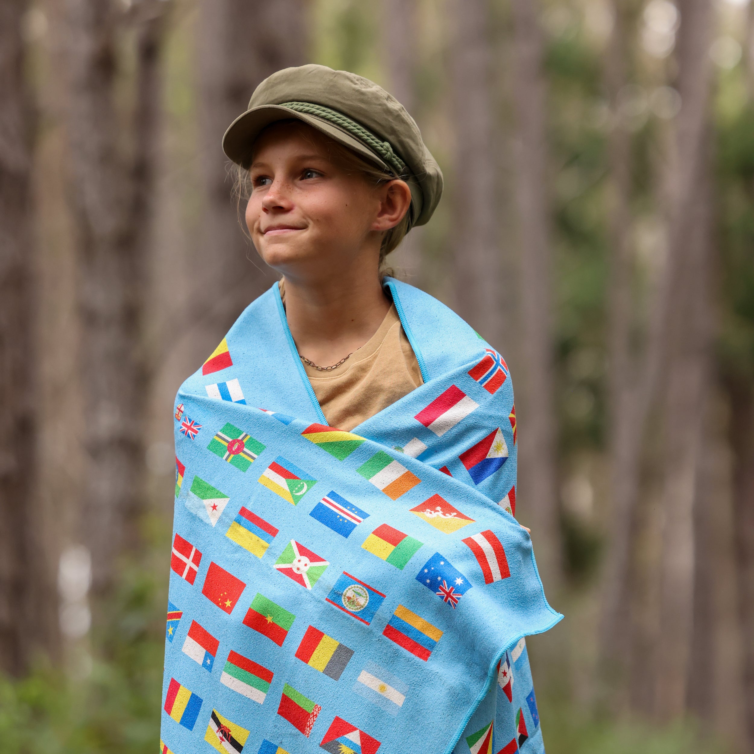 Photo of a young girl with the blue flags of the world blanket wrapped around her shoulders.