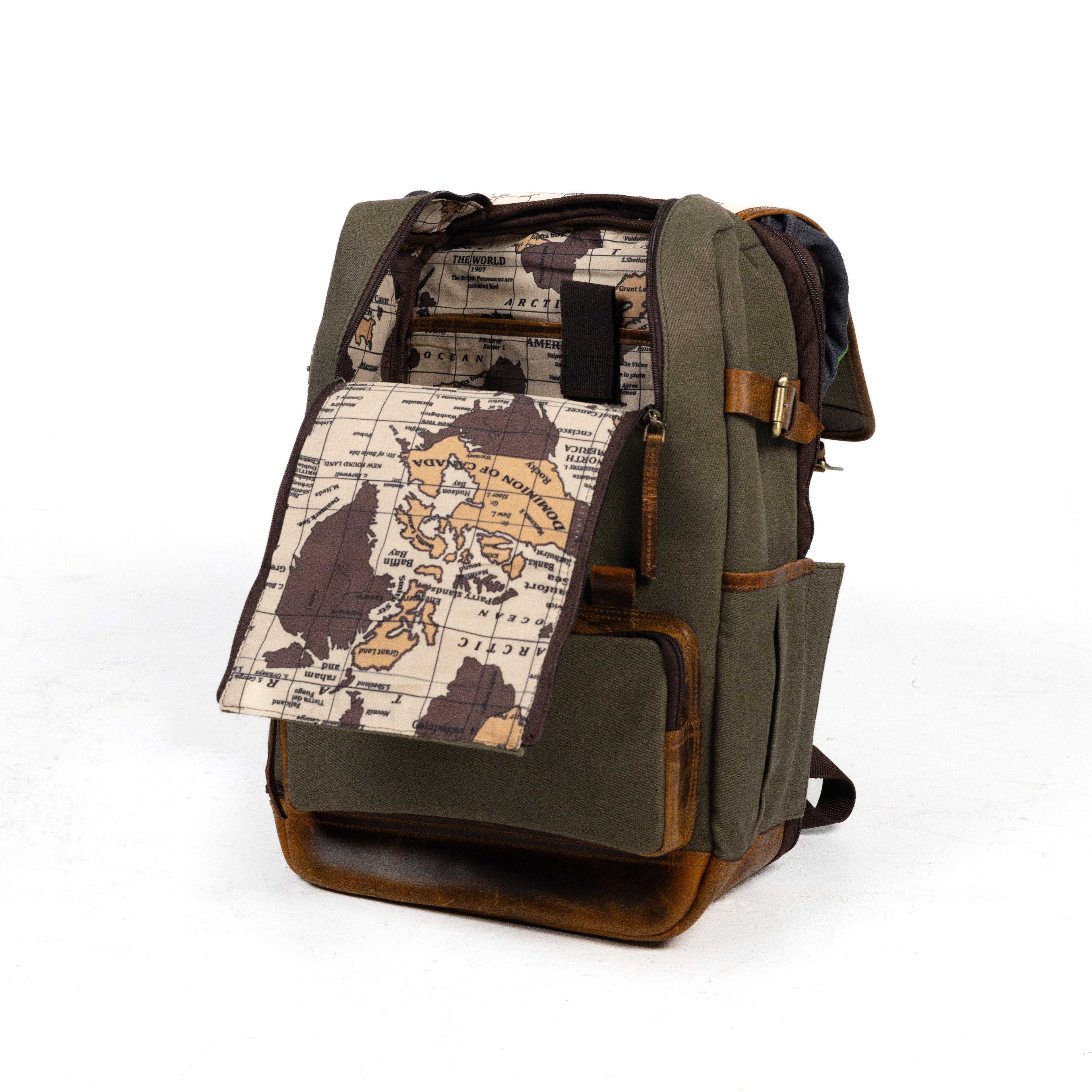 Product photo of a vintage sage canvas and leather backpack that is open to show the inside of the bag. The inside lining of the bag has a world map design.