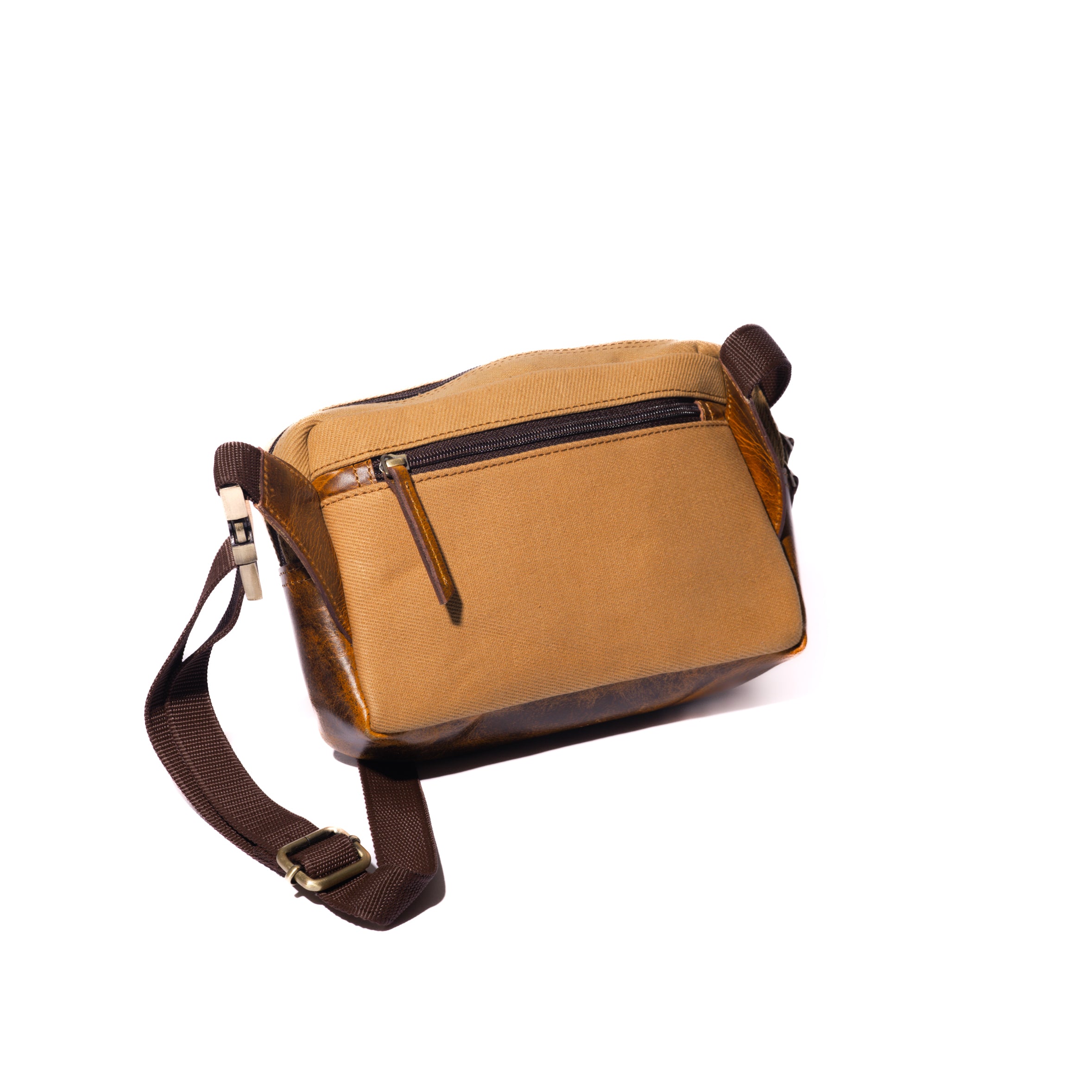 Product image the back of a tan canvas and leather crossbody belt bag with a white background.