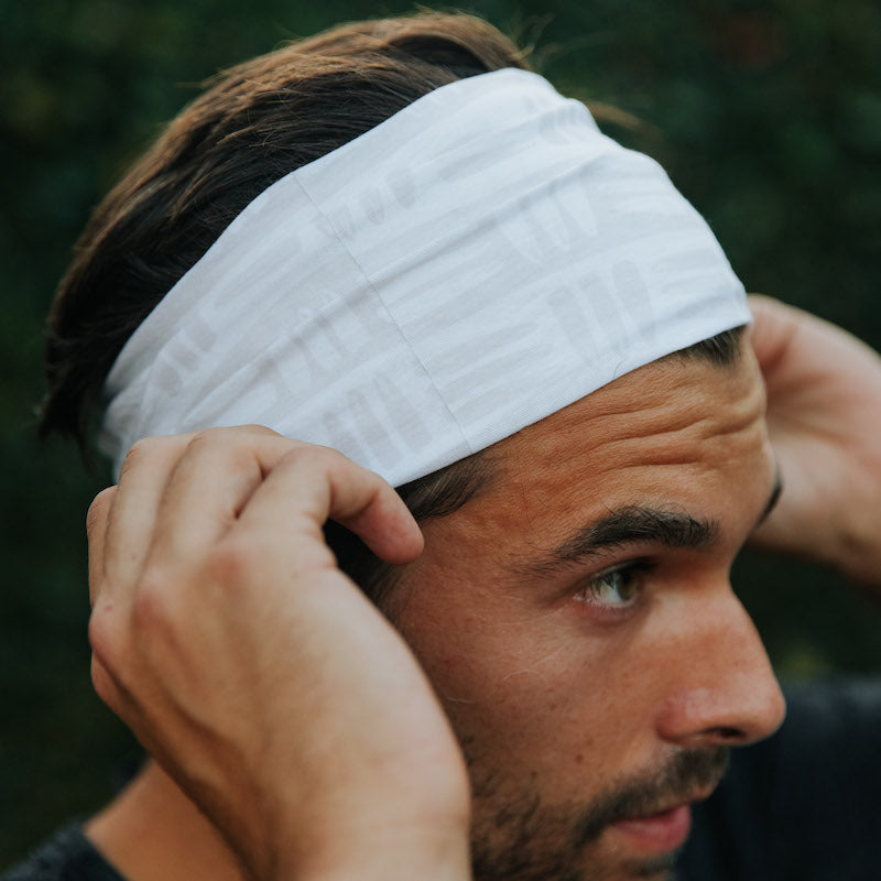 Photo of the head of man wearing a white buff around his head like a headband.