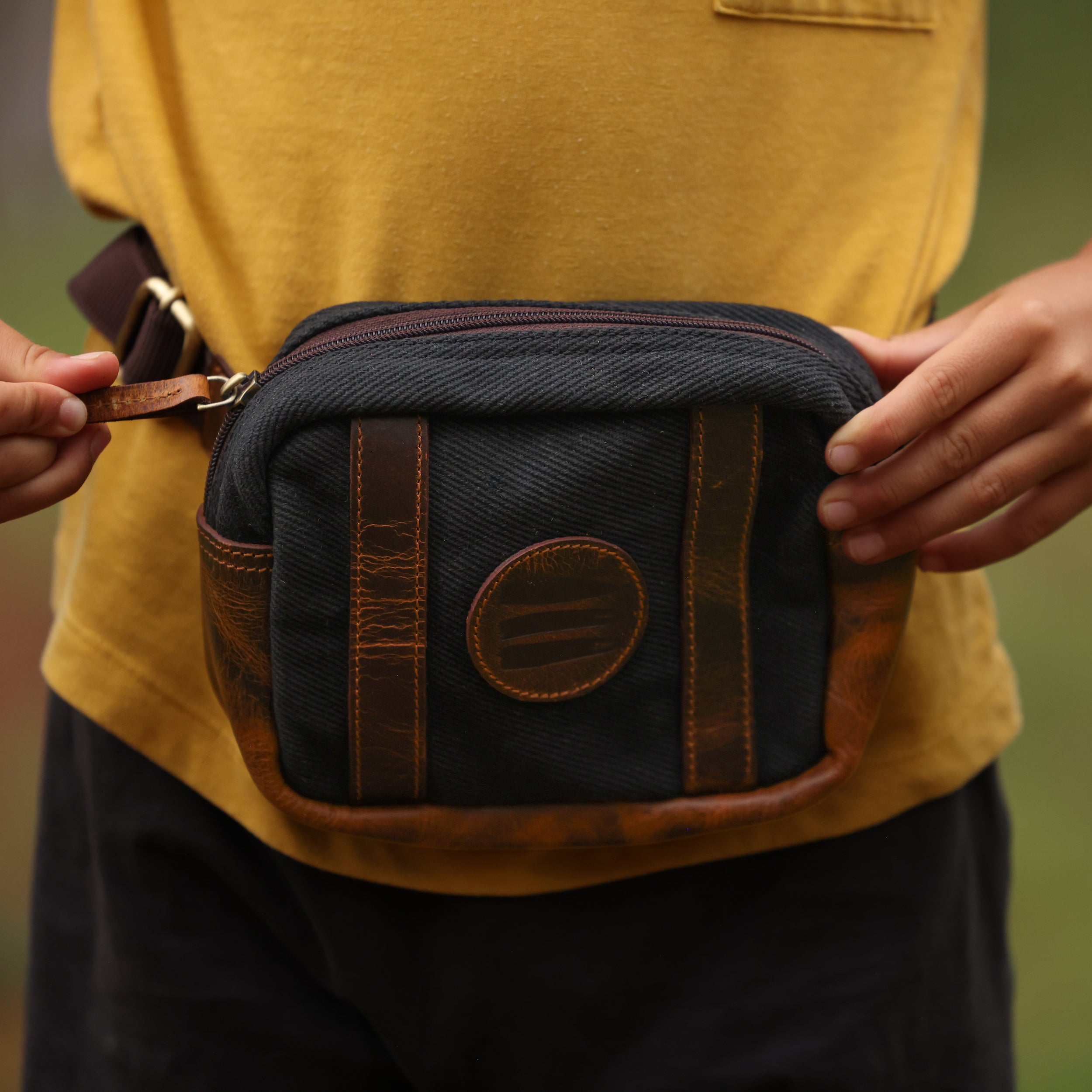 A close-up image of a black canvas and leather fanny back being worn around the hips of a child.