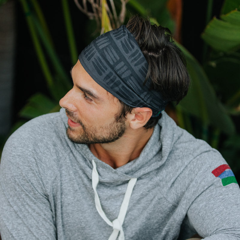 Photo of a man wearing a grey and black buff around his head like a headband.