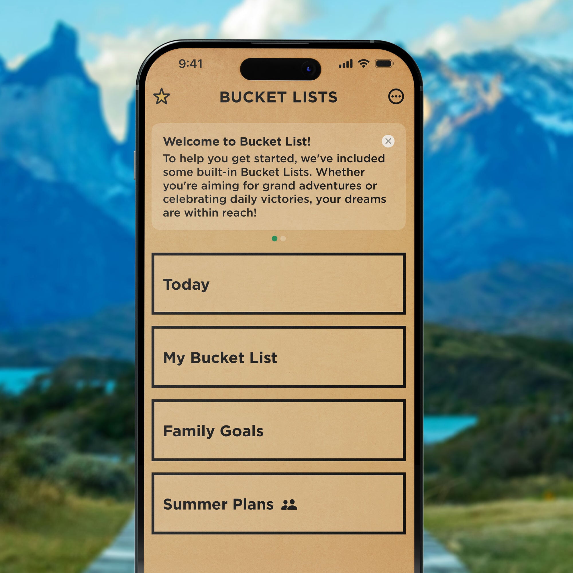 Image with a mountain background and a phone screen in the center showing what the bucket list app looks like. The bucket list app has a tan background with black text and boxes.