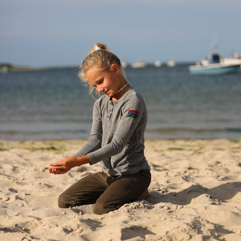 Photo of a girl on the beach wearing a grey henley.