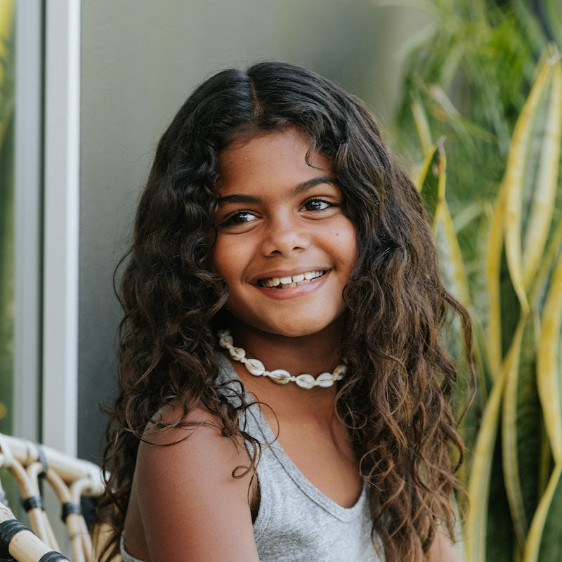 Photo of a girl wearing a strung necklace of white shells.