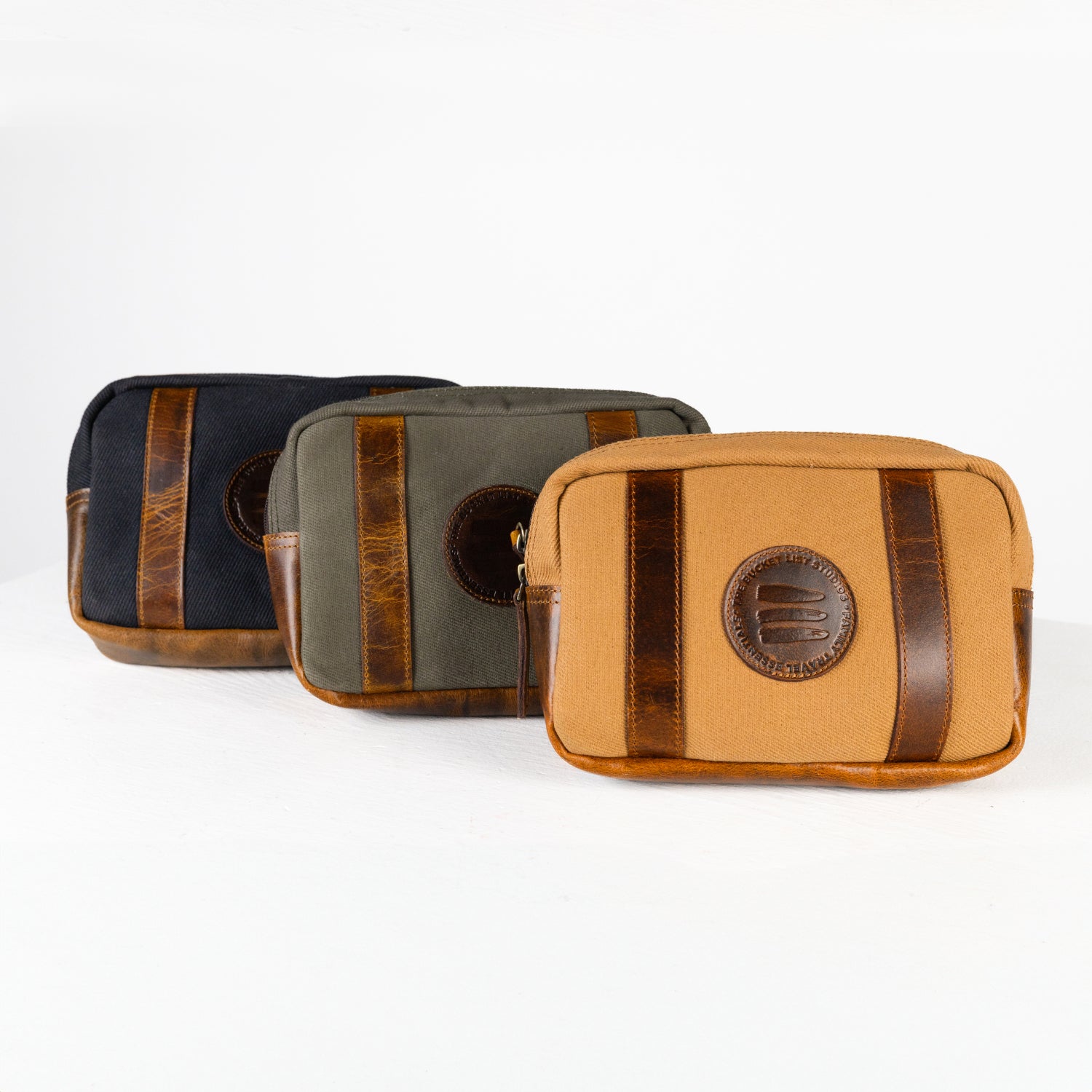 A product image of three crossbody belt bags (black, vintage sage, and tan) lined up on a white surface with a white background. 