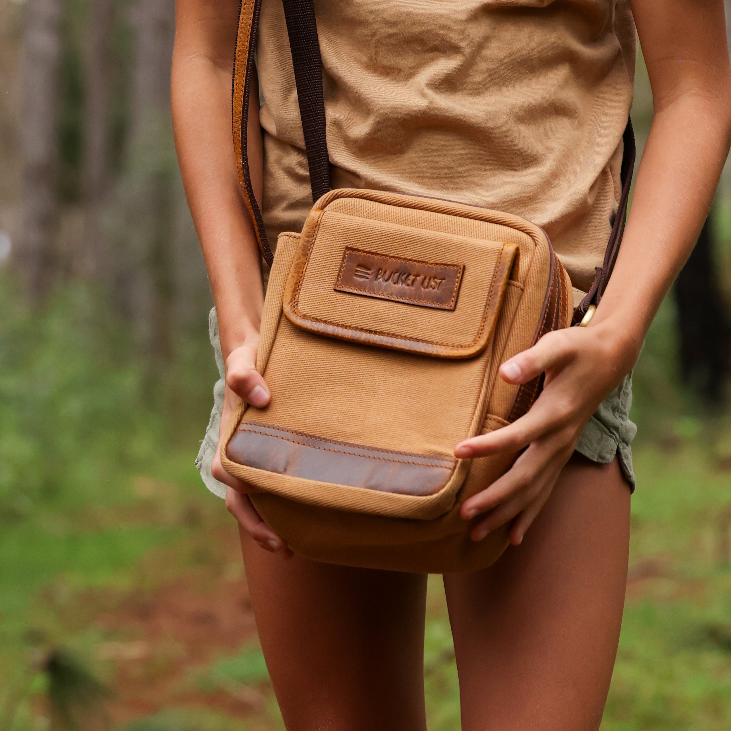 Close up photo of a girl holding a tan canvas and leather bag. 