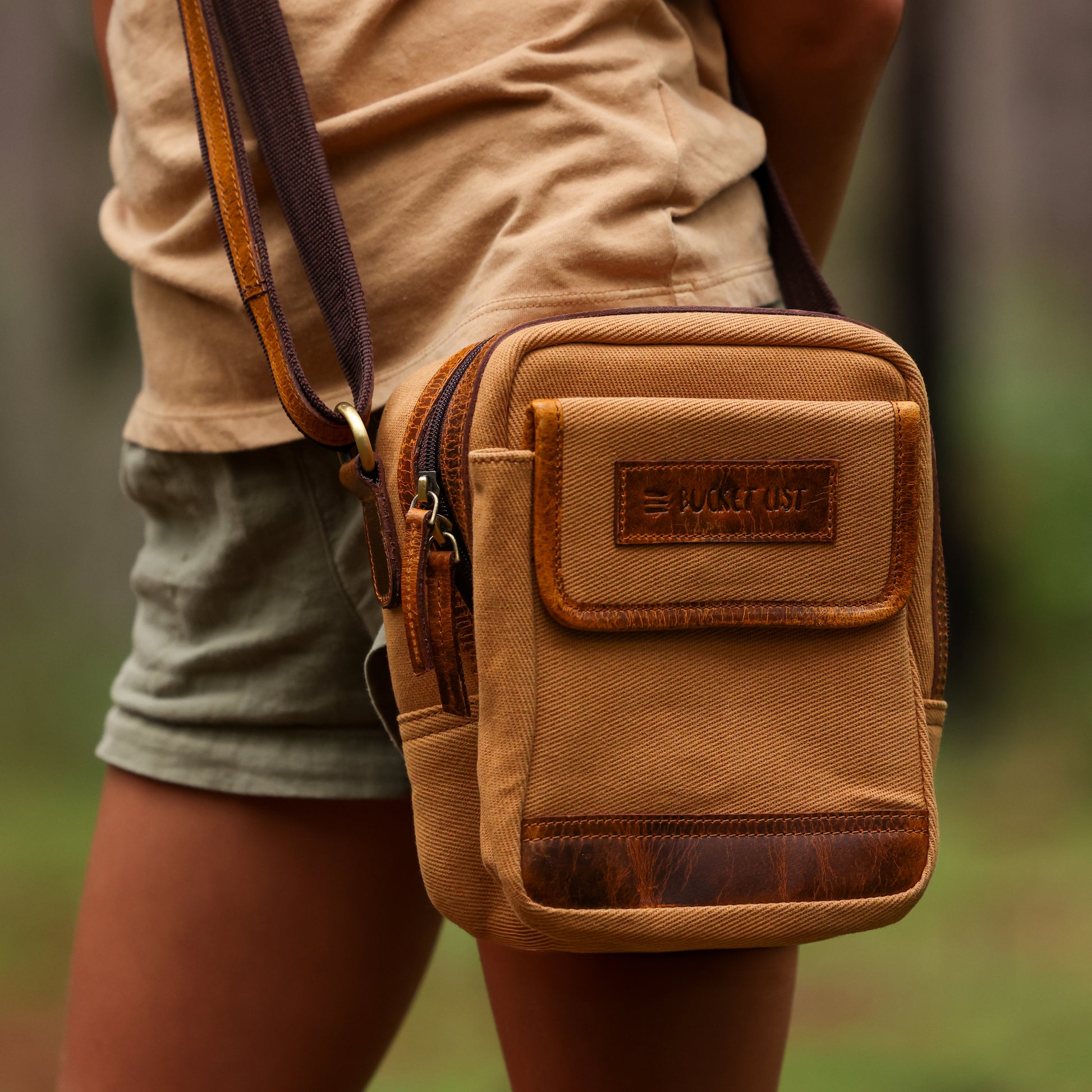 Image of girl wearing a tan sling pouch with leather accents.