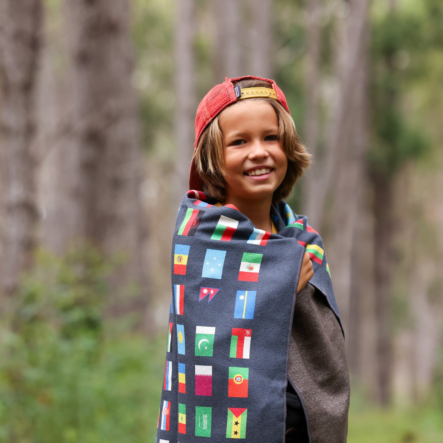 Photo of a young boy with a black flags of the world blanket wrapped around him.