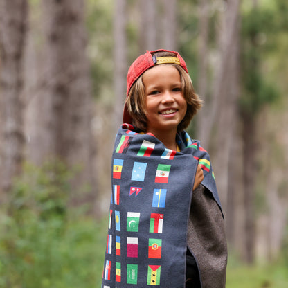 Photo of a young boy with a black flags of the world blanket wrapped around him.