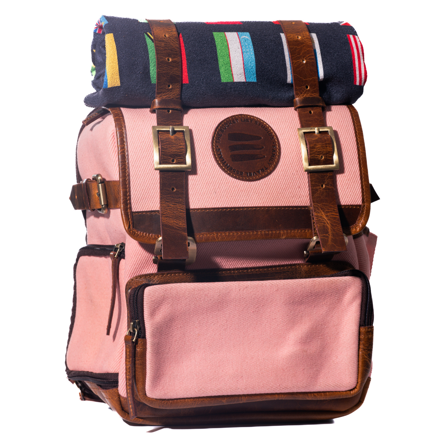 Product photo of a pink canvas and leather backpack with a black rolltop blanket on top of the backpack. 