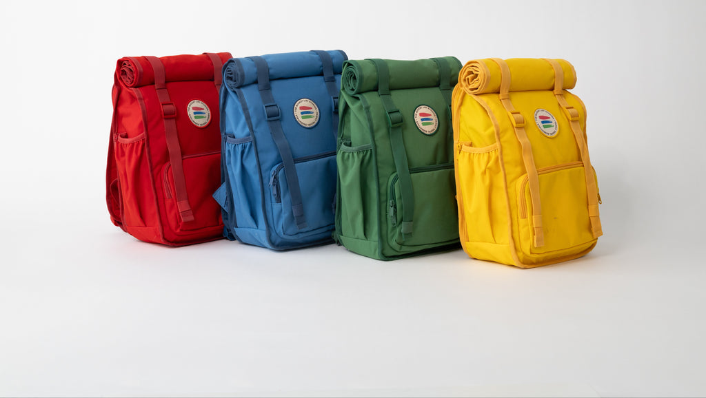 Four colorful backpacks (red, blue, green, yellow) on a white background