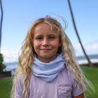 Picture of a young girl with blonde hair wearing a white buff around her neck. 