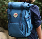 Blue backpack with a logo on a person's back against a blurred natural background