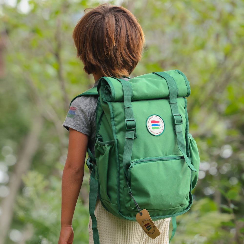 Person wearing a green backpack with a colorful patch outdoors