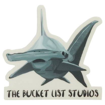 An image of a cartoon hammerhead sticker that says The Bucket List Studios at the bottom. 