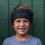 Photo of a young boy wearing a black and grey buff around his head like a headband.