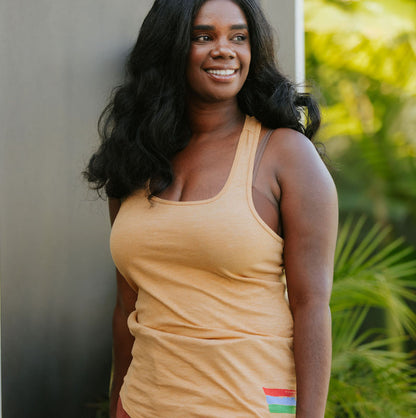 Photo of a woman wearing a mustard yellow tank top with the bucket list logo in the bottom right corner of the tank top. 